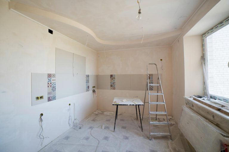 Spacious kitchen under renovation with ladder and tools, showcasing a fresh new design.